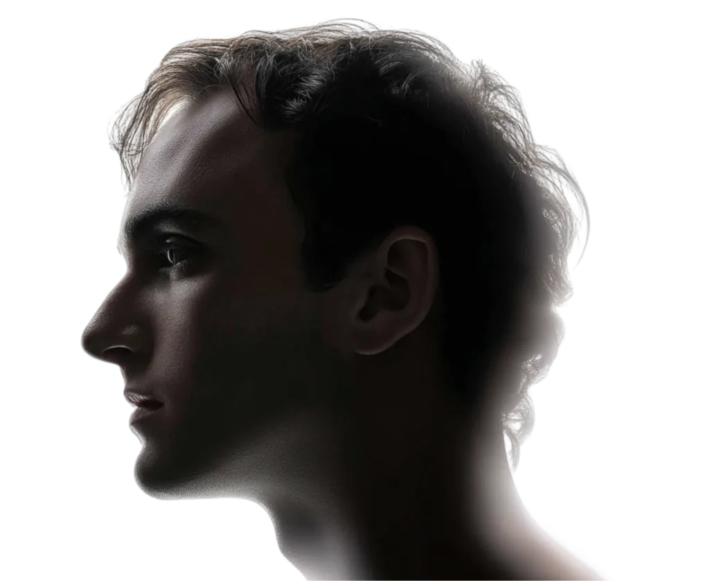 Side profile of a young man with short hair against a dark background.