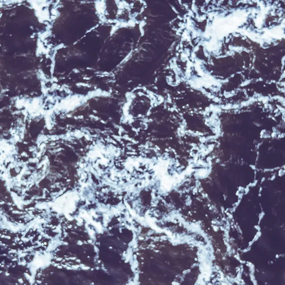 Close-up aerial view of dark ocean water with white foamy waves.