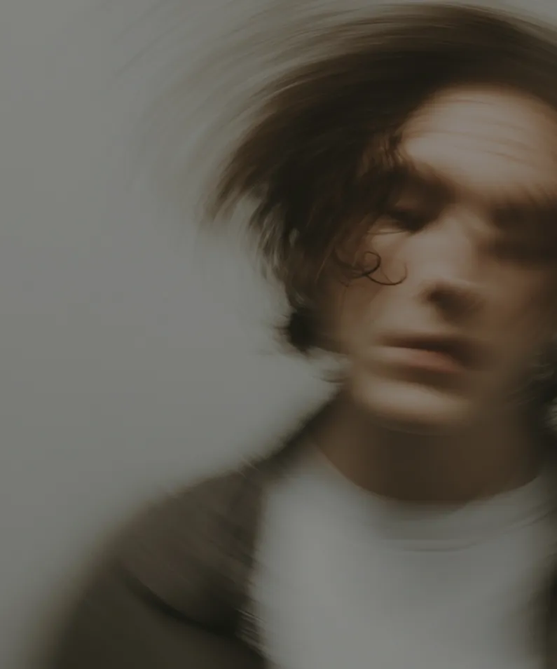 Blurred portrait of a person with dark hair in motion creating a swirling effect.